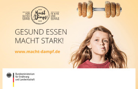 Ein Mädchen hält einen Teller mit einem Brotgesicht und verschiedenem Obst und Gemüse in der Hand