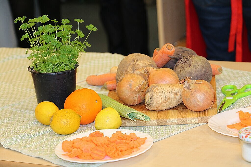 Zur Seniorenernährung und -verpflegung Ein Topf mit Petersielie und verschiedenes Gemüse und Obst auf einem Tisch